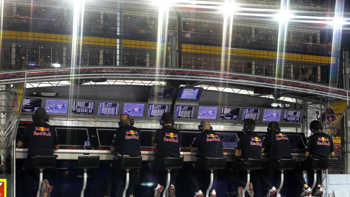 Race team paddock pit wall crew members wearing racing headsets and team shirts